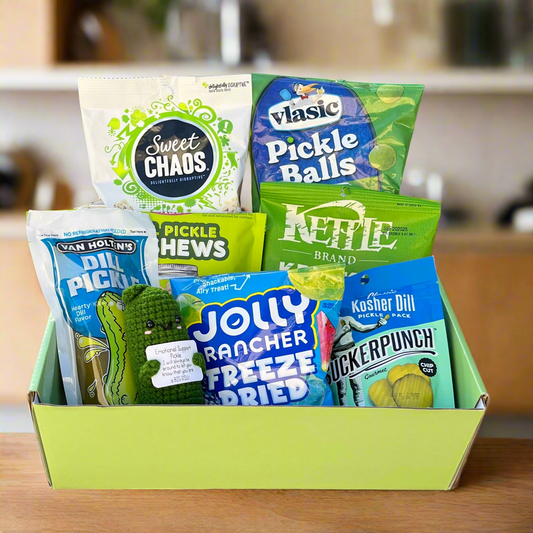 Assorted snack packages including Sweet Chaos, Vlasic Pickle Balls, Kettle Brand, Van Holt Pickles, and Jolly Rancher Freeze Dried in a green box.